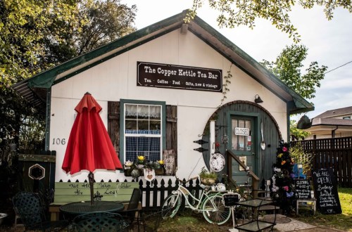 Charming tea bar with a red umbrella, bicycle decor, and a "CLOSED" sign outside a quaint building.