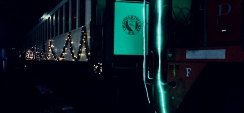A vintage train car decorated with festive lights, illuminated in a dark setting.