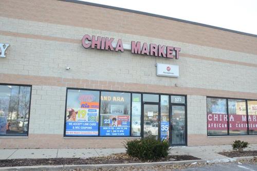 Exterior of Chika Market, featuring a sign and storefront with promotional posters and a clear blue sky.