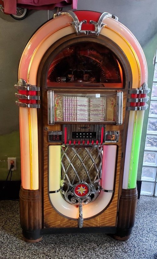 A vintage jukebox with colorful lights and a classic design, featuring a glass front and decorative details.