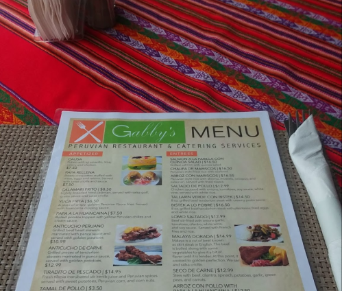 Menu from Gabby's Peruvian Restaurant featuring appetizers, entrees, and prices on a colorful tablecloth.