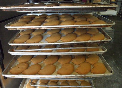 Trays stacked with freshly baked cookies cooling on a rack in a bakery.