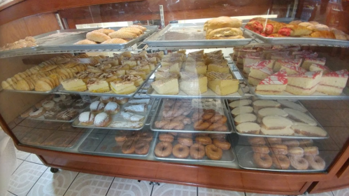 A display case filled with various baked goods, including pastries, cakes, and cookies.