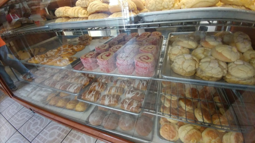 A display case filled with various baked goods, including pastries, cookies, and sweet rolls.
