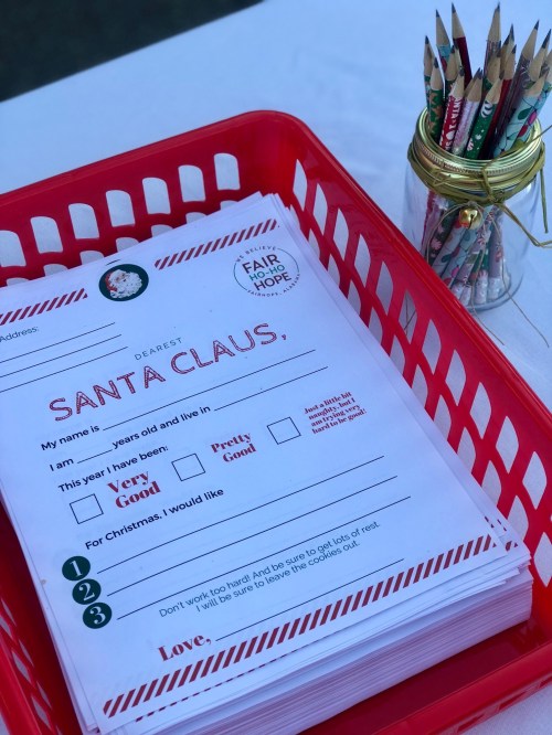 A red basket filled with letters to Santa, alongside a jar of colored pencils for writing.