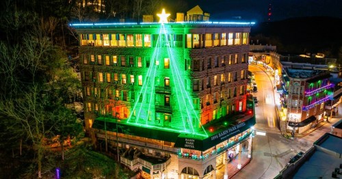 A hotel building illuminated with colorful lights shaped like a Christmas tree, topped with a star.