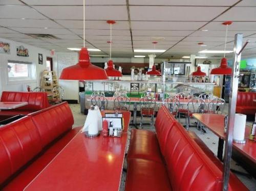 A retro diner interior featuring red booths, red pendant lights, and a bright, inviting atmosphere.