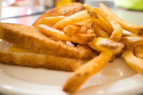 A plate with a grilled cheese sandwich and a side of golden, crispy French fries.