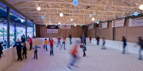 A lively indoor ice skating rink with people skating under festive lights and decorations.