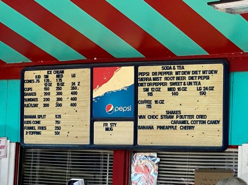 Menu board featuring ice cream, sodas, teas, and shakes with prices listed for each item. Pepsi logo at the center.