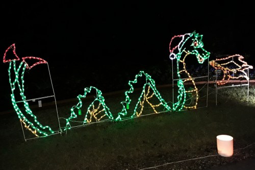 A festive dragon made of colorful lights, wearing a Santa hat, set against a dark background.