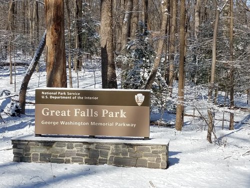 Sign for Great Falls Park, surrounded by snow-covered trees, indicating the George Washington Memorial Parkway.