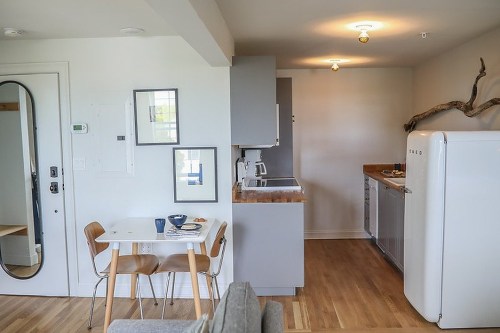 A modern kitchen and dining area with a small table, gray cabinets, and a retro-style refrigerator.