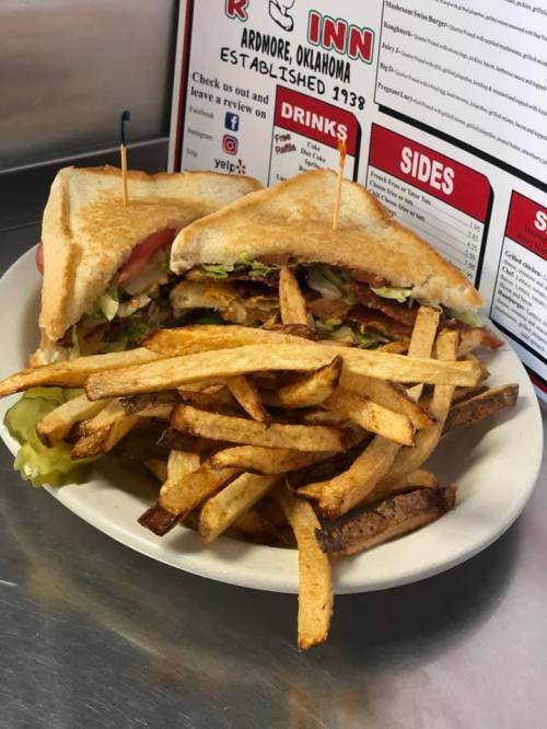 A plate with a toasted sandwich filled with lettuce, tomato, and bacon, served with a side of golden fries.