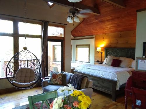 Cozy bedroom with a wooden ceiling, a hanging chair, and a large bed, featuring warm decor and natural light.