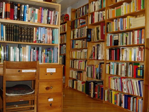 A cozy library with wooden shelves filled with books and a small desk in the foreground.