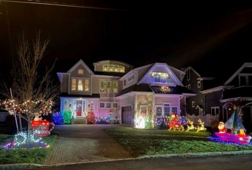 A beautifully decorated house at night, adorned with colorful Christmas lights and festive decorations in the yard.