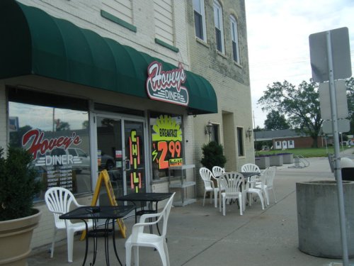 Exterior of Howey's Diner with a green awning, outdoor seating, and a sign advertising breakfast for $2.99.