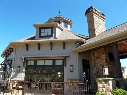 A modern building with a stone chimney, large windows, and a decorative roof against a clear blue sky.
