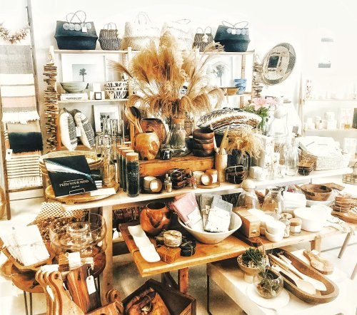 A cozy display of home goods, featuring woven baskets, pottery, and decorative items on wooden shelves and tables.