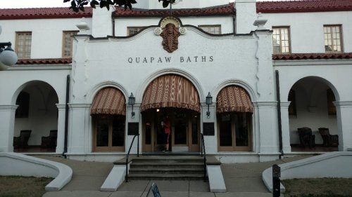 Historic building with arched entryways and striped awnings, featuring the sign "Quapaw Baths" above the entrance.