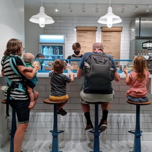 A family with two children and a baby at a counter, enjoying milkshakes in a cozy café setting.