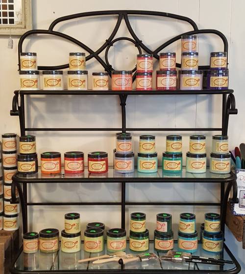 A black metal shelf displaying various colorful paint cans arranged in neat rows.