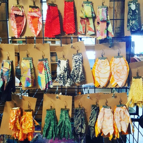 Colorful fabric earrings displayed on a grid, featuring various patterns and shapes in vibrant hues.