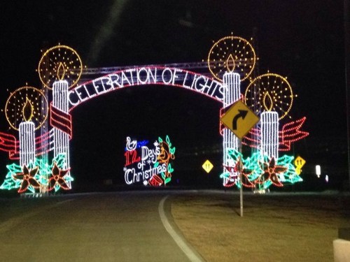 Colorful holiday lights form an archway reading "Celebration of Lights," with candles and festive decorations.