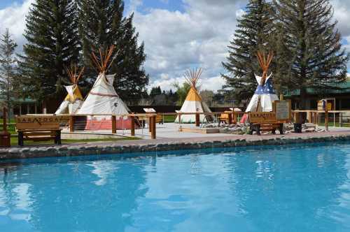 A serene outdoor scene featuring tipis near a swimming pool, surrounded by trees and a cloudy sky.