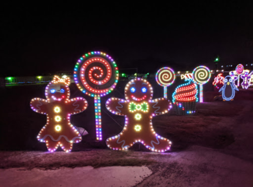 Colorful illuminated gingerbread figures and lollipops in a festive display at night.