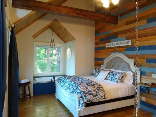 Cozy bedroom with a wooden accent wall, a large bed, and a bathtub by the window, featuring warm lighting.