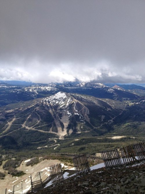 A panoramic view of a mountainous landscape with snow-capped peaks and cloudy skies above.