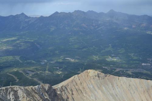 A panoramic view of rugged mountains and lush valleys under a clear sky, showcasing natural beauty and terrain.