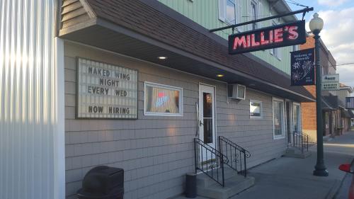 Exterior of Millie's restaurant with a sign advertising "Naked Wing Night" and "Now Hiring."