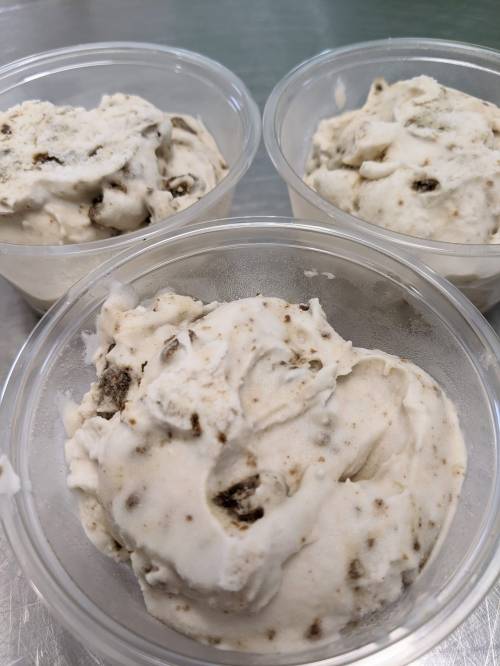 Three clear containers filled with creamy, cookie-flavored ice cream with chocolate chunks.