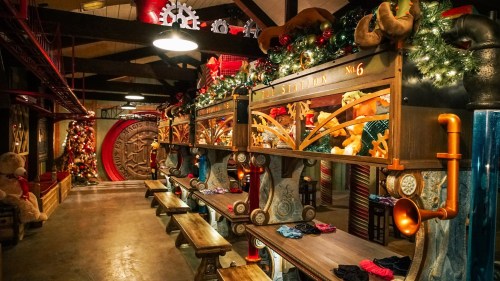 A festive workshop with wooden benches, decorated with toys and holiday lights, creating a cheerful atmosphere.