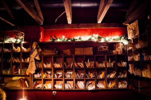 A cozy interior with wooden shelves filled with envelopes, illuminated by warm string lights and festive greenery.
