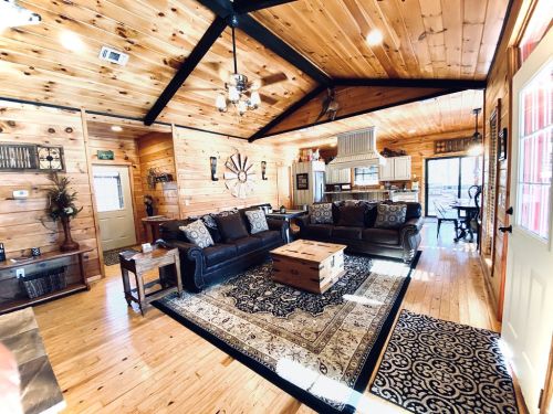 Cozy wooden living room with leather sofas, a coffee table, and a patterned rug, featuring a bright, open layout.