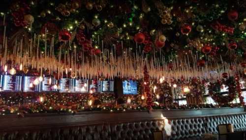 A festive restaurant interior adorned with Christmas decorations, including lights, ornaments, and icicle garlands.