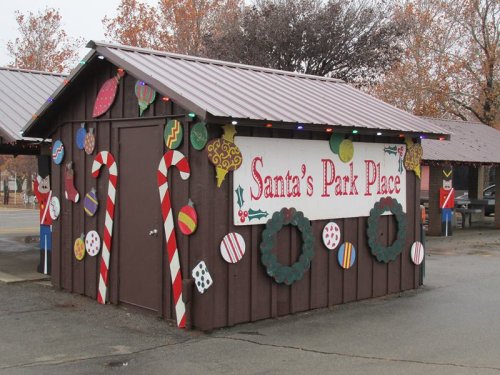 A festive wooden cabin decorated with candy canes, ornaments, and wreaths, labeled "Santa's Park Place."