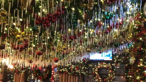 A festive display of colorful ornaments and icicle lights hanging from a decorated ceiling, creating a holiday atmosphere.