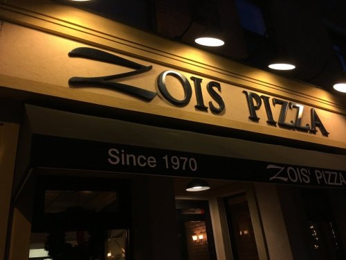 Sign for Zois Pizza, featuring the name prominently and the text "Since 1970" below it, illuminated at night.