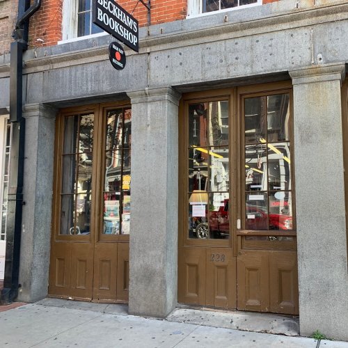 Exterior of Beckham's Bookshop with large glass doors and a sign above, located at 228 on a brick street.