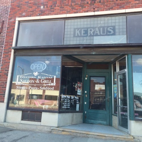 Exterior view of a saloon and grill with a sign reading "Open" and a brick building facade.
