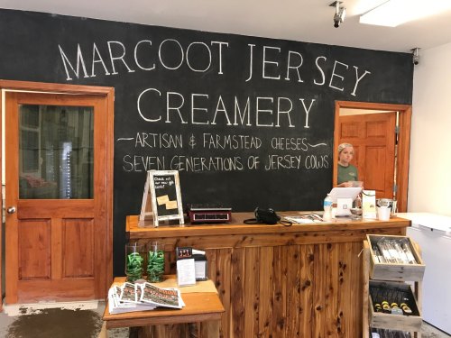 Interior of Marcot Jersey Creamery featuring a chalkboard sign, wooden counter, and a person in the background.