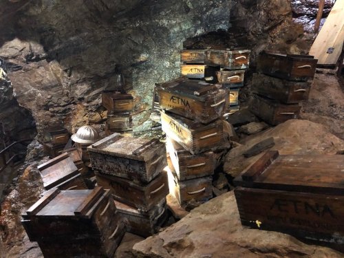 A dimly lit underground mine with stacked wooden crates against rocky walls.