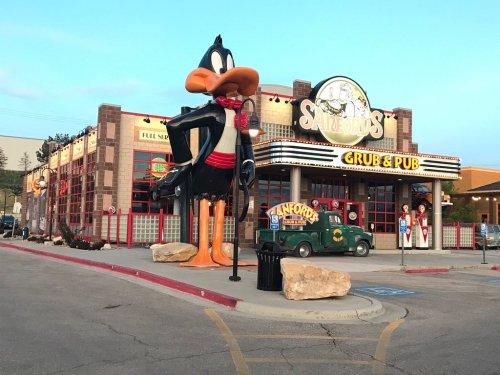 A large Daffy Duck statue stands outside Sanford's Grub & Pub, a colorful restaurant with a playful theme.