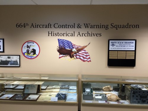 Display of the 664th Aircraft Control & Warning Squadron's historical archives, featuring memorabilia and a patriotic mural.
