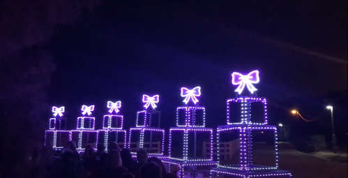Colorful illuminated gift boxes with bows, lined up at night, creating a festive atmosphere.